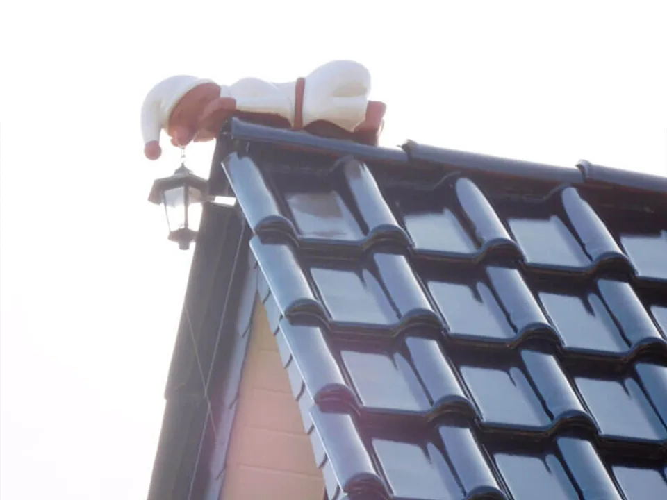 Dachspitze mit glänzenden Dachziegeln und Dekorfigur – Detailarbeit vom Dachdeckermeister.