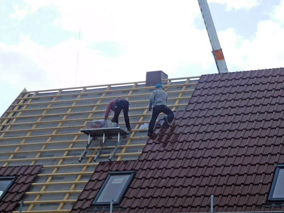 Dachdecker bei der Neueindeckung eines geneigten Daches – sichere und präzise Handwerksarbeit.