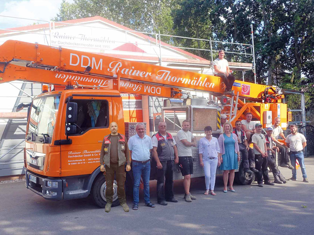 Team des Dachdeckermeisterbetriebs Rainer Thormählen vor Servicefahrzeug und Arbeitsbühne – Handwerksqualität seit 1995.
