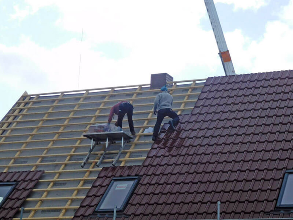 Dachdecker bei der Neueindeckung eines geneigten Daches – sichere und präzise Handwerksarbeit.